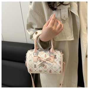 Détail de l'imprimé ours et cœur sur un sac Boston blanc avec nœud papillon rose