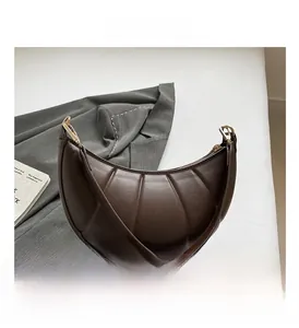 Detail of dark brown leather crescent bag with unique radial pleated texture and metallic buckle