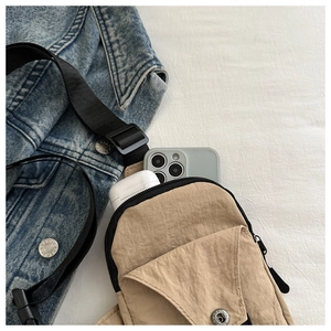 Detail view of khaki canvas crossbody bag showing interior space for phone and earphones