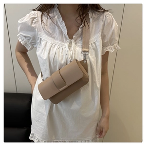 Model wearing khaki matte leather crossbody bag with wide textile shoulder strap detail