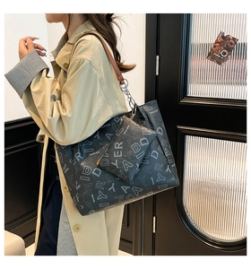 Close-up of vintage tote bag set with branded print and brown leather chain straps