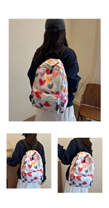 Detail view of the multi-colored heart print canvas backpack with front zipper pocket