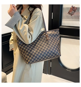 Detail of a large brown checkered tote bag with Z-pattern on a khaki trench coat