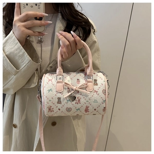 Détail du nœud rose et du pendentif en cœur sur un sac Boston au style mignon