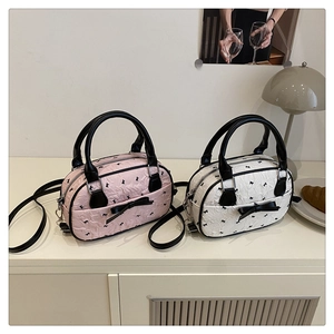 Pink and white textured mini Boston bags with black bow patterns and crossbody straps