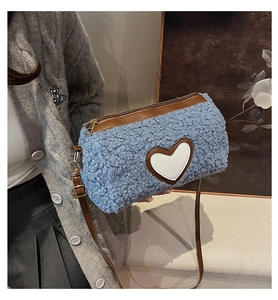 Détail du sac cylindrique en peluche avec patch cœur blanc et bandoulière en cuir