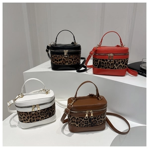 Detailed view of four leopard print barrel bags in black, red, white and coffee on a stand