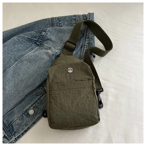 Detail of army green nylon chest bag with metallic M logo and durable zipper pocket