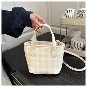 Detail view of small plaid tote bag with cream leather handles and detachable metal hooks