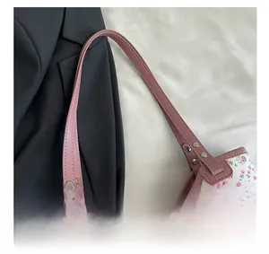 Détail de la poignée en similicuir rose avec rivets argentés sur un sac fourre-tout