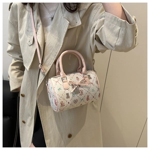 Détail du sac Boston rose avec motifs d'ours porté à l'épaule par un mannequin