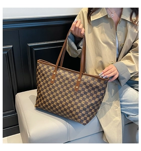Detail view of the vintage brown checkered tote bag with leather straps and gold rivets