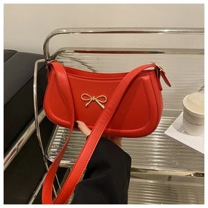 Detailed close-up of a red baguette bag with a decorative gold metallic bow ornament
