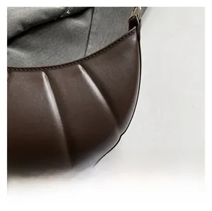 Detail shot of the textured pleated brown leather surface on a stylish hobo bag