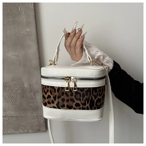 Detail of leopard print vanity bag with white patchwork and golden zipper closure