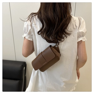 Detailed back view of a dark brown matte leather crossbody bag worn by a model