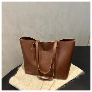 Close-up of vintage brown tote bag with pebble leather texture and gold lettering logo