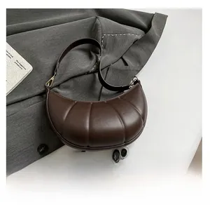 Detail view of dark brown croissant bag compared with a smartphone for size reference