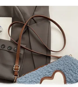 Détail du sac en peluche bleu avec patch cœur, bandoulière en cuir brun et boucle dorée