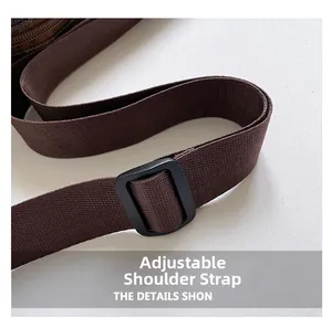 Detail of a brown woven shoulder strap with an adjustable black plastic buckle