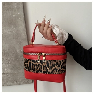Detail of red bucket bag with leopard print panel and golden double zipper closure