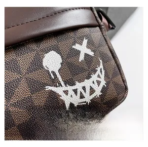 Detail of vintage patterned crossbody bag with white graffiti smiley face and brown leather
