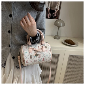 Détail du sac Boston avec imprimés d'ours, garniture rose et pendentif coeur en métal