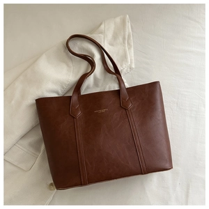 Close-up of vintage brown leather tote bag showing lychee texture and gold letter printing