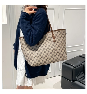 Detail of large monogram tote bag with brown leather handles worn over the shoulder