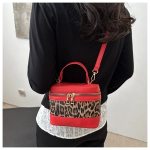 Detailed view of red leopard print bucket bag with gold zippers and adjustable strap
