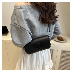 Side view of a matte black leather shoulder bag with a flap cover and silver metal buckles