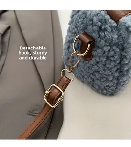 Détail du sac bleu en laine d'agneau avec bandoulière en cuir brun et boucles dorées