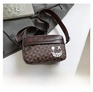Brown geometric crossbody bag with white graffiti face and smartphone for size reference