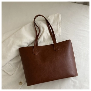 Detailed view of the brown tote bag's vintage leather texture and arrow-shaped stitching