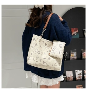 Détail du sac cabas crème avec imprimé lettres et bandoulière en cuir brun et chaîne