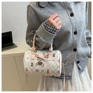 Détail du sac Boston avec motifs d'ours, nœud rose et pendentif en métal en cœur