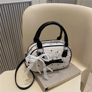 White pleated Boston bag with black bow print, lace pearl charms, and leather straps