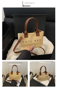 Detail of straw tote bag showing brown leather handles and TOTE BAG embroidery