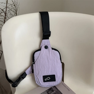 Light purple nylon crossbody chest bag with adjustable black strap on white chair