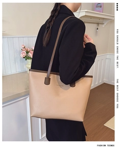 Bolso tote beige con bordes marrones mostrado por modelo en un ambiente moderno