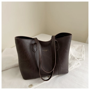 Macro view of dark brown PU leather texture and gold embossed logo on a large tote bag