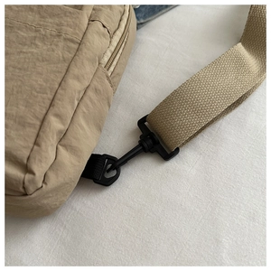 Detail of khaki nylon chest bag showing sturdy black plastic buckle and durable strap