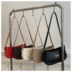 Row of minimalist leather baguette bags with golden bow accents in five versatile colors