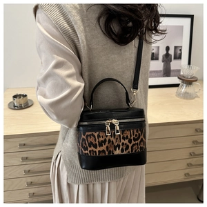 Close-up of leopard print patchwork crossbody bag with gold zippers worn by model