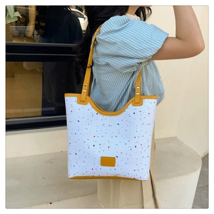 Détail d'un sac cabas floral avec lanières en cuir jaune porté par un mannequin