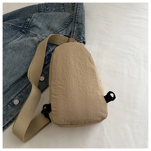Macro view of beige nylon crossbody bag with textured fabric and adjustable strap buckle