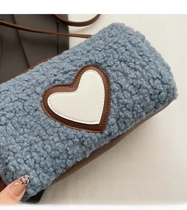 Détail du sac cylindre bleu en polaire peluche avec patch cœur et bandoulière marron