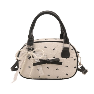 Chic cream bowling bag with black bow prints and a large pearl lace pendant
