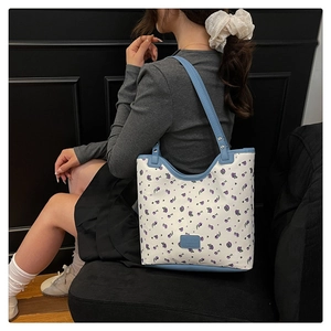 Détail d'un grand sac cabas fleuri avec bandoulières bleu clair et rivets argentés chic