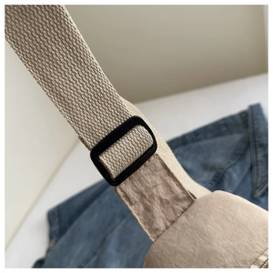 Detail of adjustable woven shoulder strap and plastic buckle on nylon crossbody bag